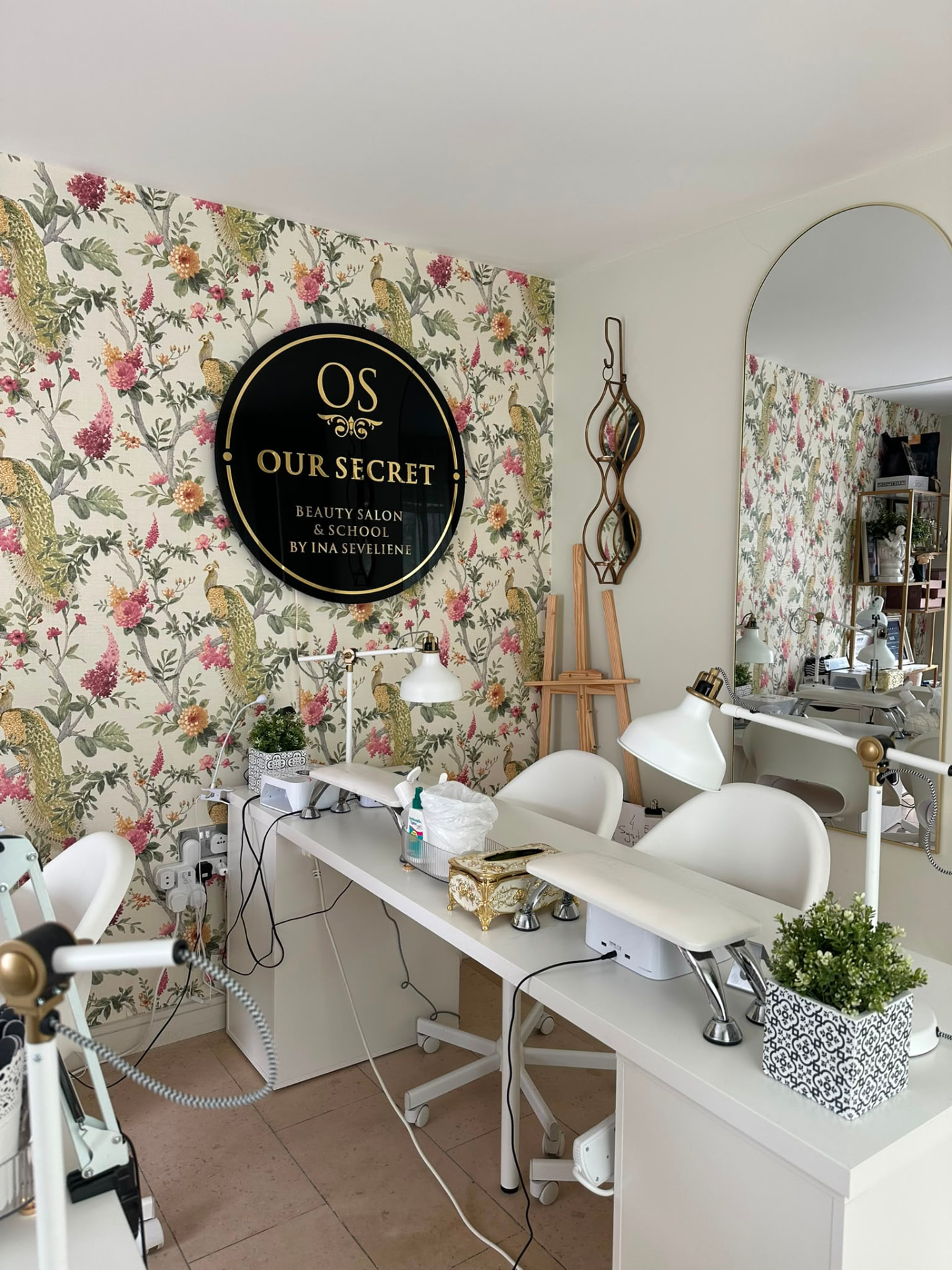 Our Secret salon training wall with logo and manicure stations